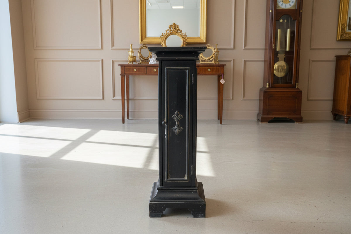 Black wooden cabinet with glass doors in a room with a concrete floor.