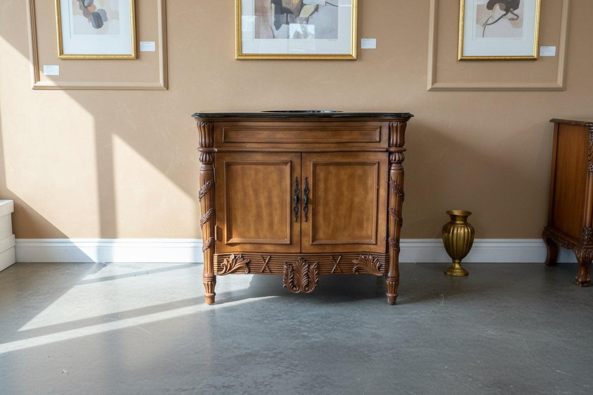 Wooden vanity with black countertop in a room with furniture and boxes.